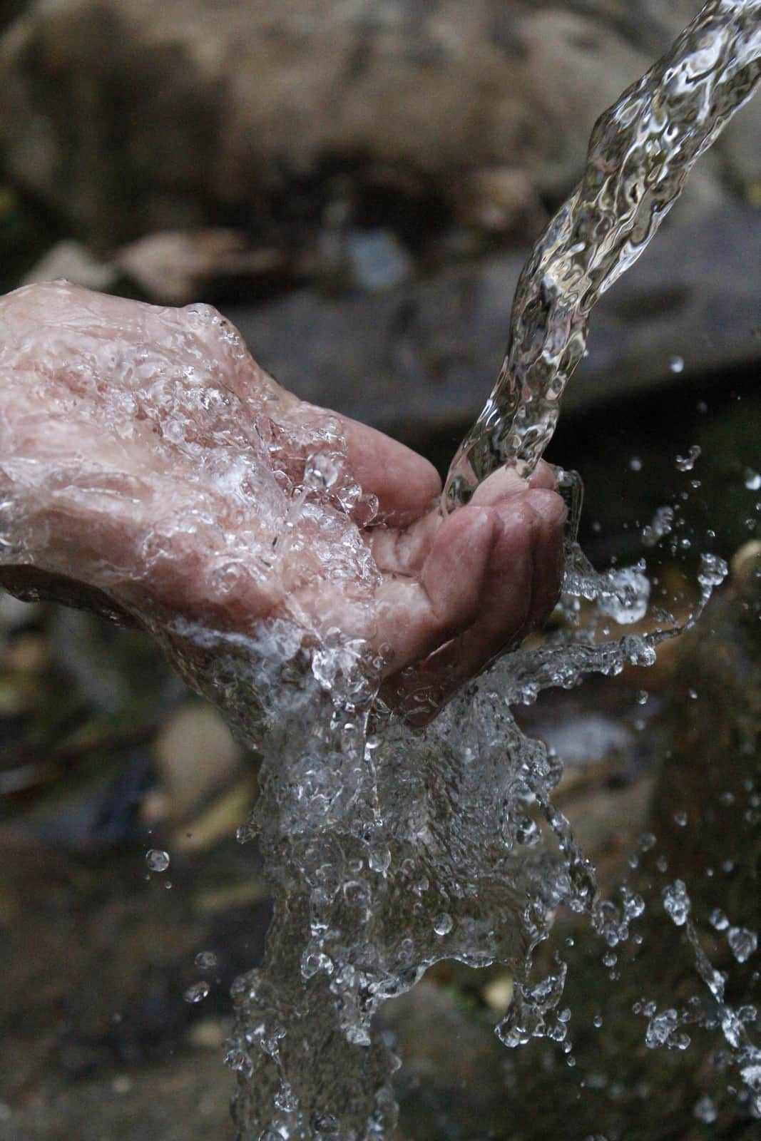 Hands held beneath a stream of flowing water
