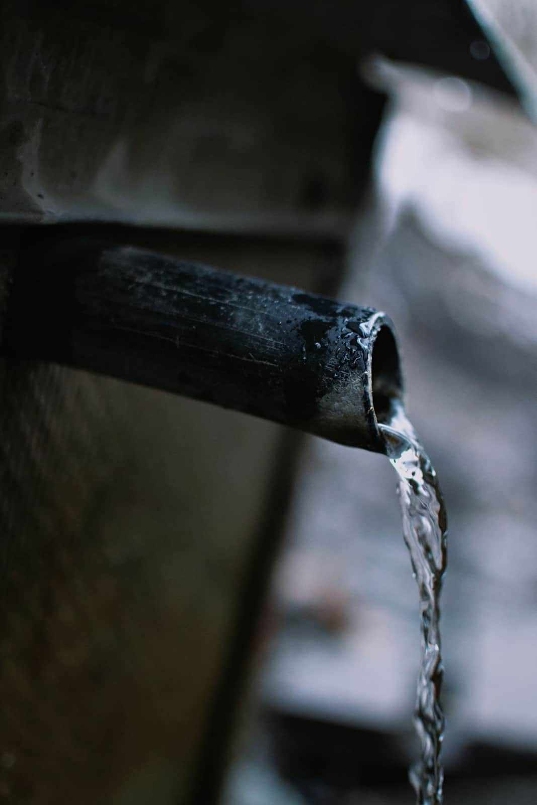 Water trickling from the end of a dark pipe